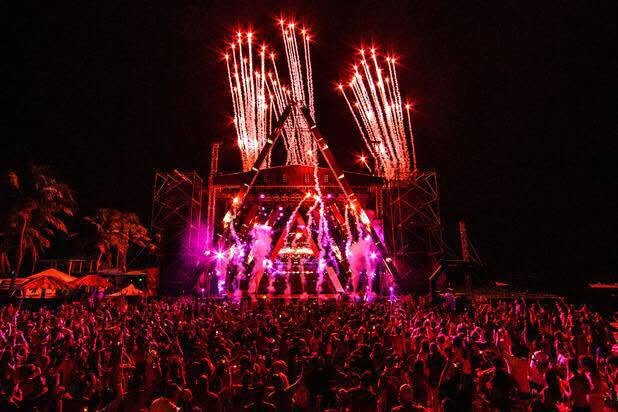 Beachfront concert stage with red lighting and fireworks