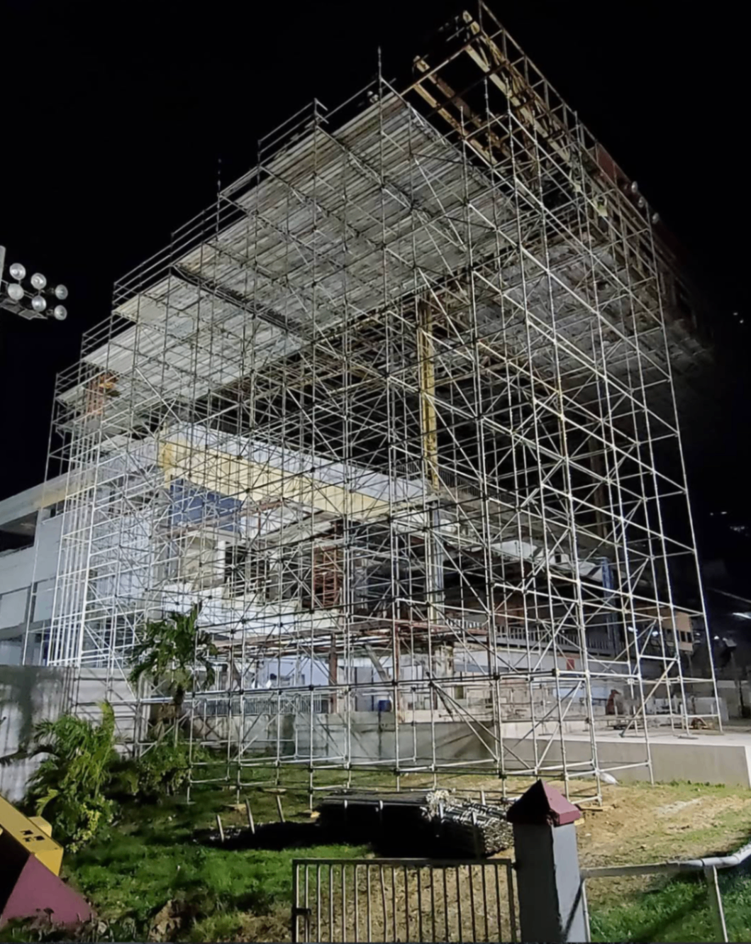 Nighttime scaffold tower installation around a building facade